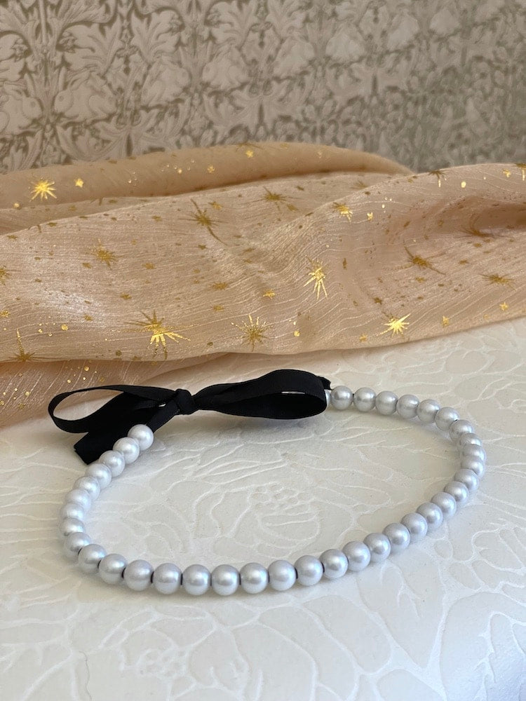 Handmade Historically inspired regency era pearl choker necklace in black, on a floral puff.