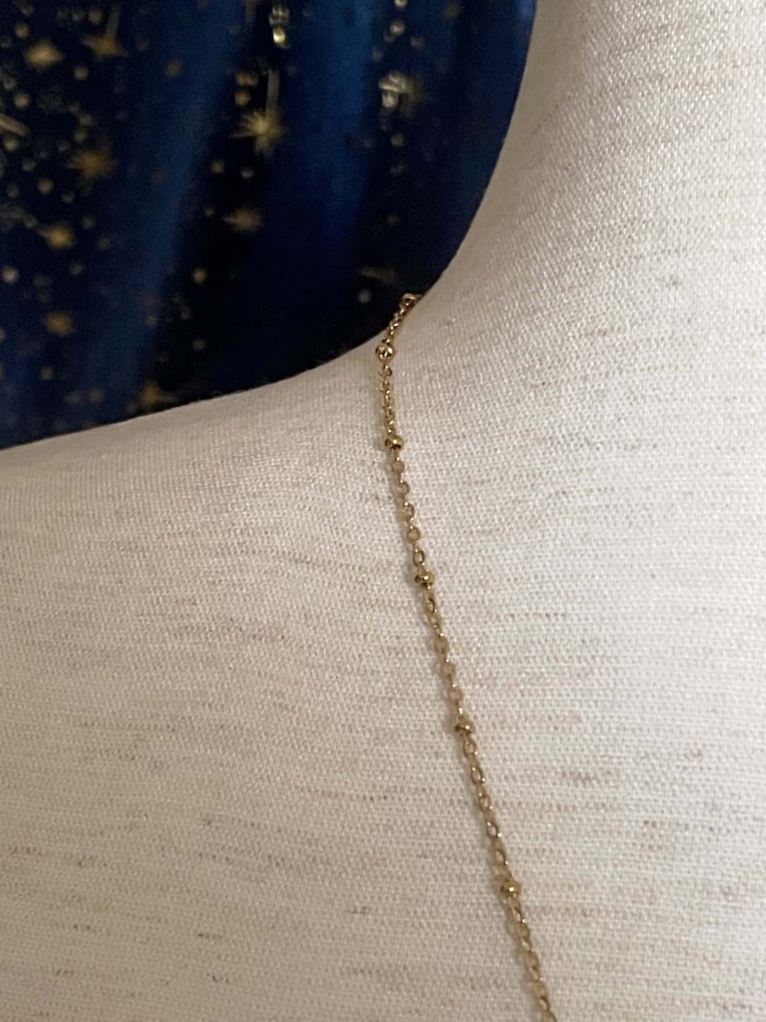 A Handmade Historically Inspired Medieval Hand Pendant Necklace with Real Baroque Pearl Dangle and Celestial Star Charms on a Metal Beaded Chain Necklace in Gold.