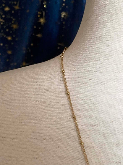 A Handmade Historically Inspired Medieval Hand Pendant Necklace with Real Baroque Pearl Dangle and Celestial Star Charms on a Metal Beaded Chain Necklace in Gold.