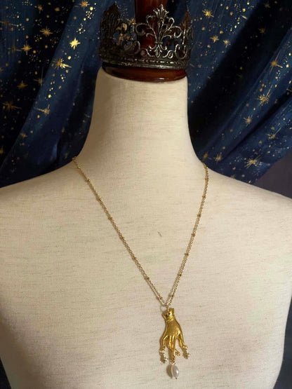 A Handmade Historically Inspired Medieval Hand Pendant Necklace with Real Baroque Pearl Dangle and Celestial Star Charms on a Metal Beaded Chain Necklace in Gold.