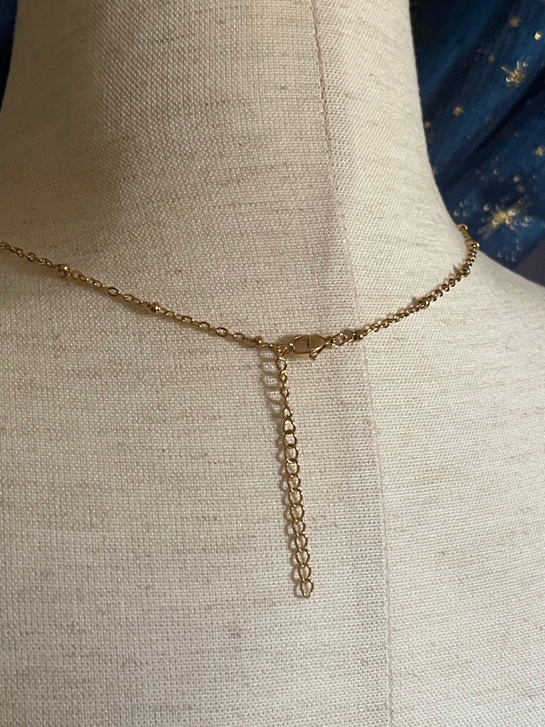 A Handmade Historically Inspired Medieval Hand Pendant Necklace with Real Baroque Pearl Dangle and Celestial Star Charms on a Metal Beaded Chain Necklace in Gold.