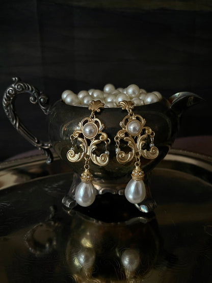 A pair of gold-colored Renaissance Inspired Ornate Flourish Earrings with Pearl Drops.
