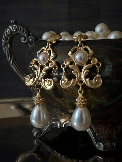 A pair of gold-colored Renaissance Inspired Ornate Flourish Earrings with Pearl Drops.