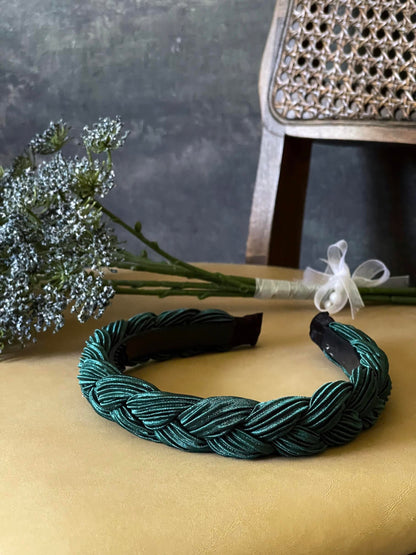 A historically inspired vintage style braided headband in dark forest green is pictured with a floral bouquet in front of an art history backdrop.