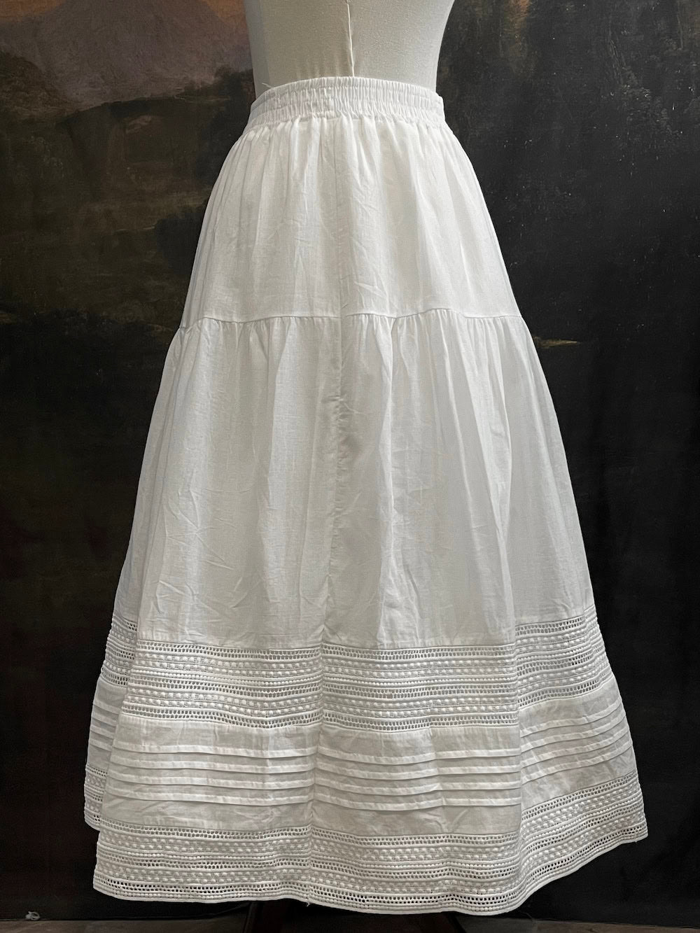 A white cotton victorian and baroque style historical fashion inspired petticoat maxi skirt with crochet lace inlay and pleated details 