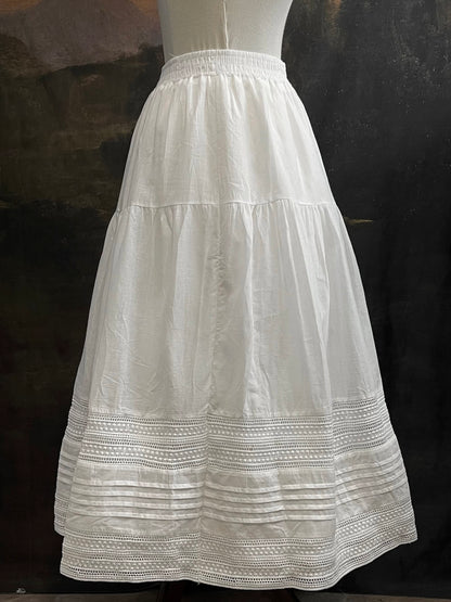 A white cotton victorian and baroque style historical fashion inspired petticoat maxi skirt with crochet lace inlay and pleated details 
