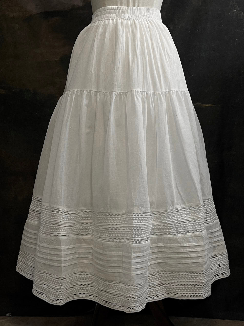 A white cotton victorian and baroque style historical fashion inspired petticoat maxi skirt with crochet lace inlay and pleated details 
