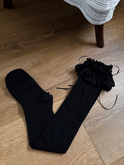 Historically Inspired Cotton Knee-High Socks with ruffled Lace Trim and ribbon ties in gothic Black on a cottagecore wooden floor.
