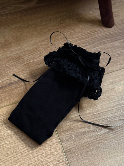 Historically Inspired Cotton Knee-High Socks with ruffled Lace Trim and ribbon ties in gothic Black on a cottagecore wooden floor.