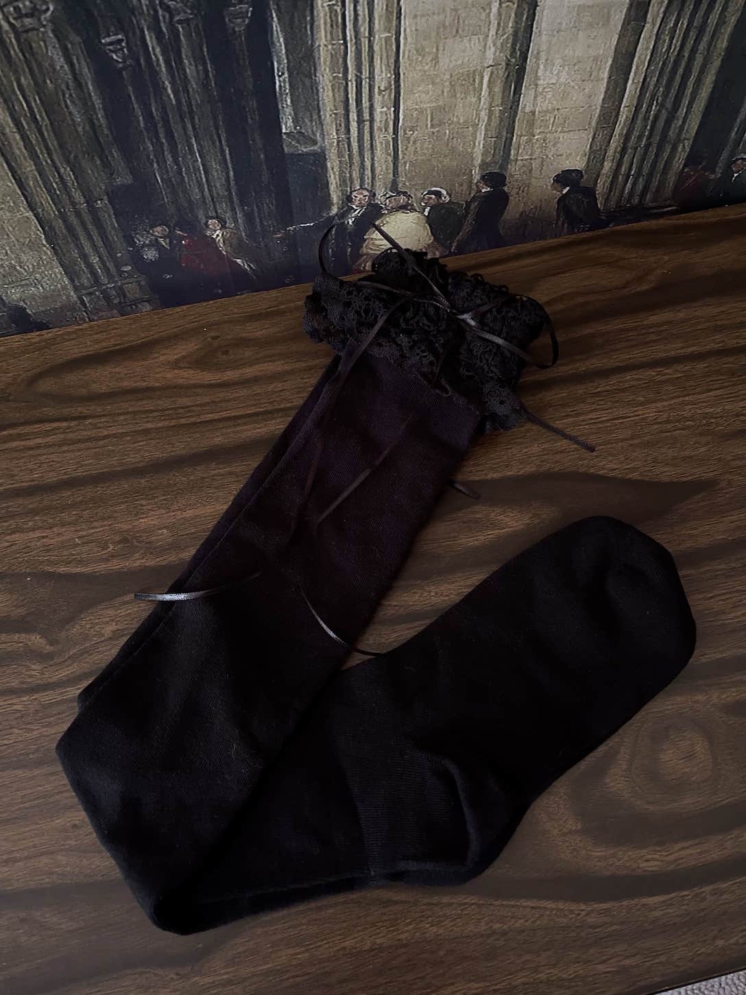Historically Inspired Cotton Knee-High Socks with Lace Trim in  gothic Black in front of a historical painting backdrop.