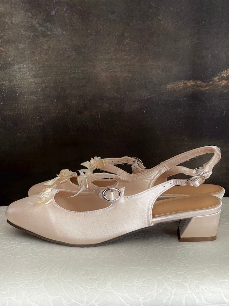 Historically inspired Regency & Rococo Inspired Satin Slipper Heels with Rosette Appliques in Champagne, pictured on a historical painting set.