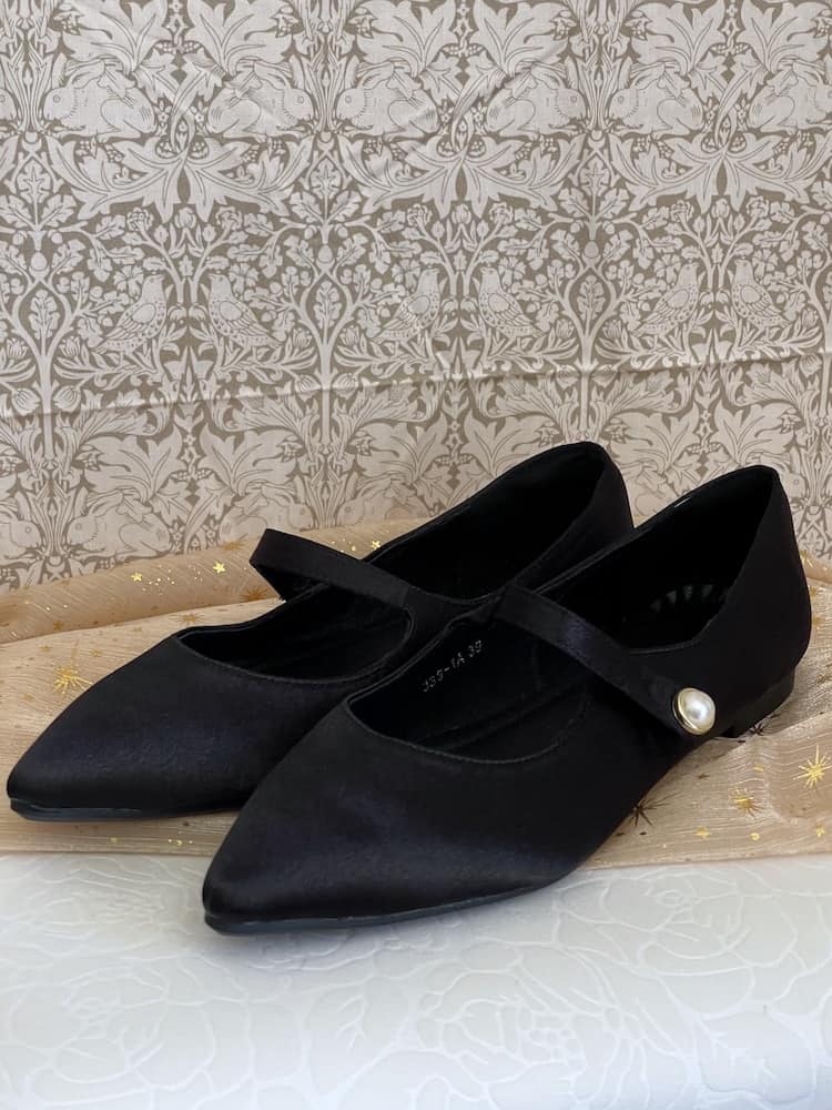 A pair of historically inspired Medieval & Renaissance Satin Pointed Toe Poulaine Flat shoes in Gothic Black with pearl accent.