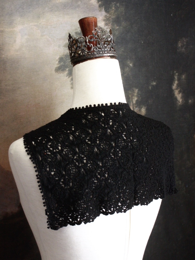 Historically Inspired Floral Crochet Folk Shawl / Capelet in Gothic Black on a mannequin in front of a painting backdrop. Victorian, renaissance, medieval.