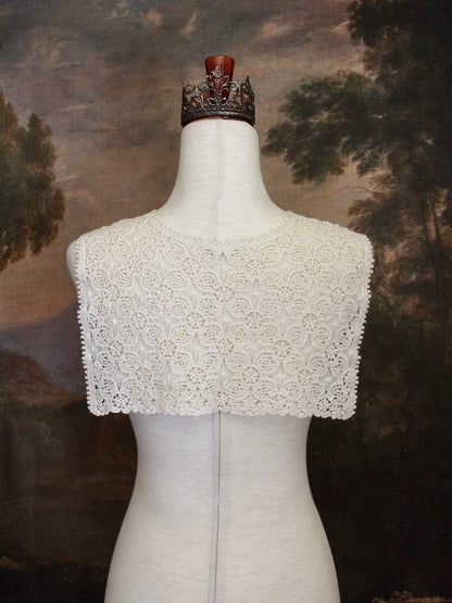 Historically Inspired Floral Crochet Folk Shawl / Capelet in Ivory on a mannequin in front of a painting backdrop. Victorian, renaissance, medieval.