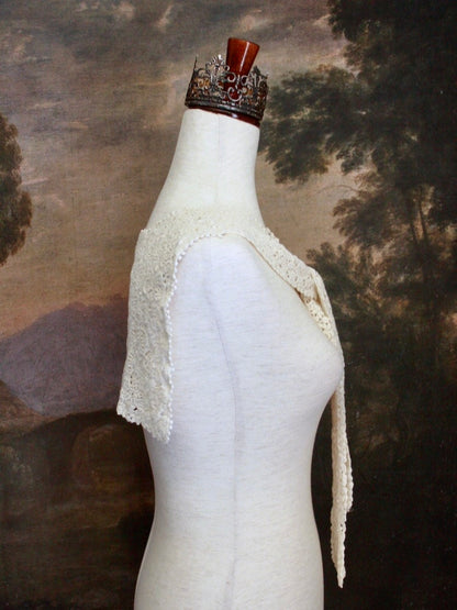 Historically Inspired Floral Crochet Folk Shawl / Capelet in Ivory on a mannequin in front of a painting backdrop. Victorian, renaissance, medieval.