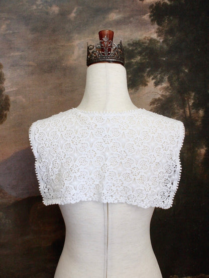 Historically Inspired Floral Crochet Folk Shawl / Capelet in White on a mannequin in front of a painting backdrop. Victorian, renaissance, medieval.