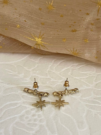 A pair of historically inspired fantasy cosmic constellation star earrings in gold pictured on a whimsigoth set.