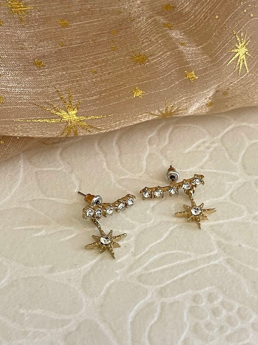 A pair of historically inspired fantasy cosmic constellation star earrings in gold pictured on a whimsigoth set.