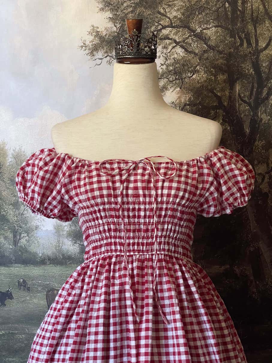 A historically inspired cottage vintage style bardot off shoulder milkmaid red gingham maxi dress with shirred bodice and puff sleeves.