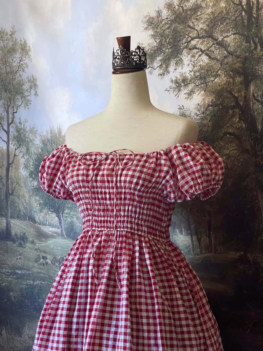 A historically inspired cottage vintage style bardot off shoulder milkmaid red gingham maxi dress with shirred bodice and puff sleeves.