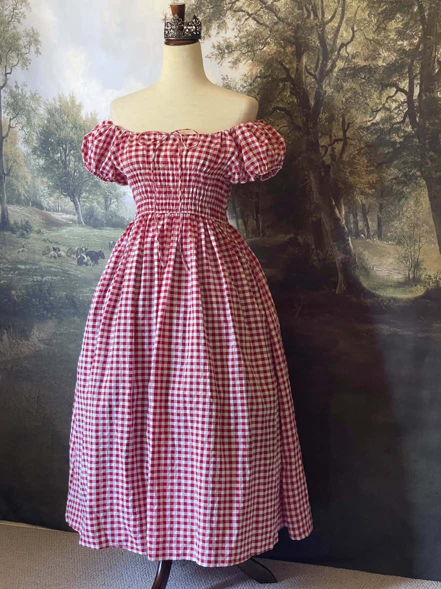 A historically inspired cottage vintage style bardot off shoulder milkmaid red gingham maxi dress with shirred bodice and puff sleeves.