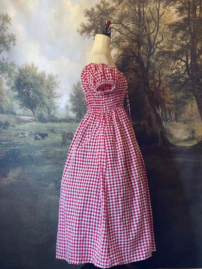 A historically inspired cottage vintage style bardot off shoulder milkmaid red gingham maxi dress with shirred bodice and puff sleeves.