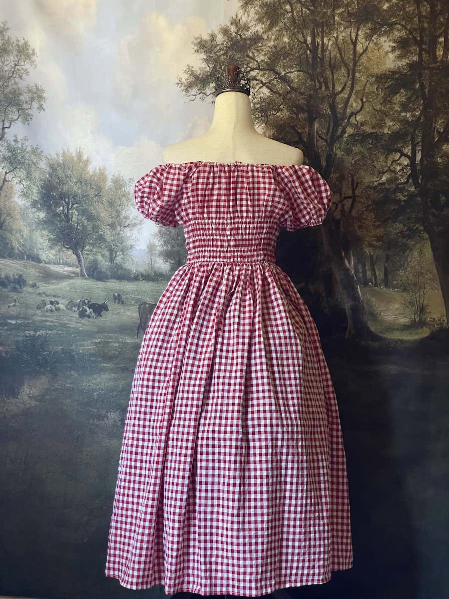 A historically inspired cottage vintage style bardot off shoulder milkmaid red gingham maxi dress with shirred bodice and puff sleeves.