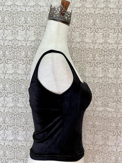 A historically inspired gothic black velvet ruched milkmaid bustier top is pictured on a mannequin in front of a William Morris Wallpaper.