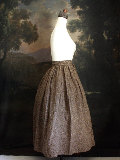 Historically Inspired victorian era peasant turn of the century  Printed Floral Cotton Maxi Skirt in Dusty Brown, pictured on a mannequin in front of a classical painting. 