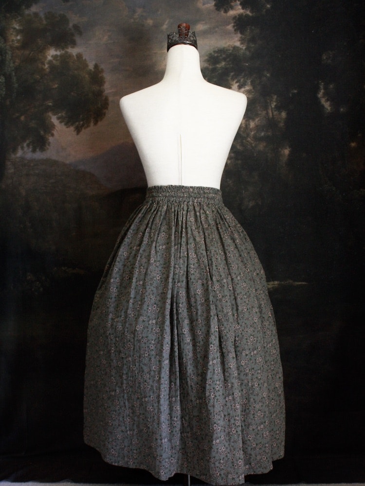Historically Inspired victorian era peasant turn of the century  Printed Floral Cotton Maxi Skirt in Dusty Sage Green pictured on a mannequin in front of a classical painting. 