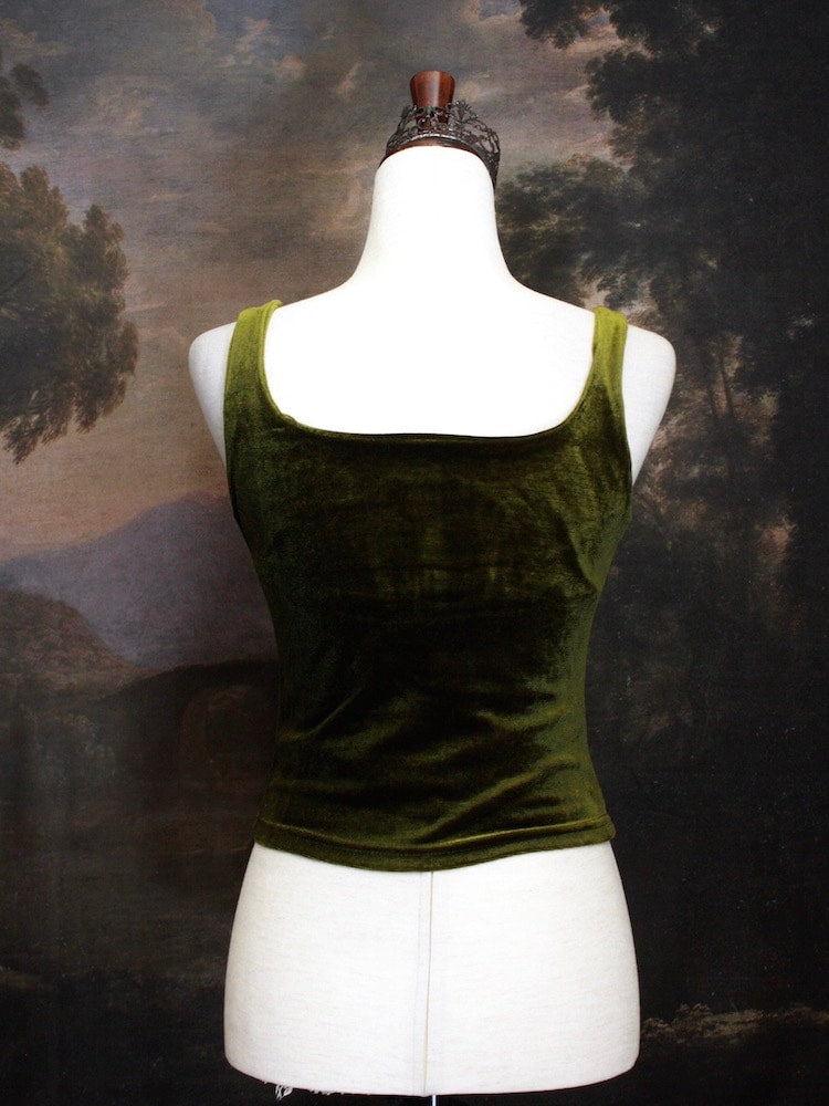 A Historically Inspired medieval fantasy Velvet Milkmaid Bustier Top in Moss Green in front of a historical painting backdrop of a forest.