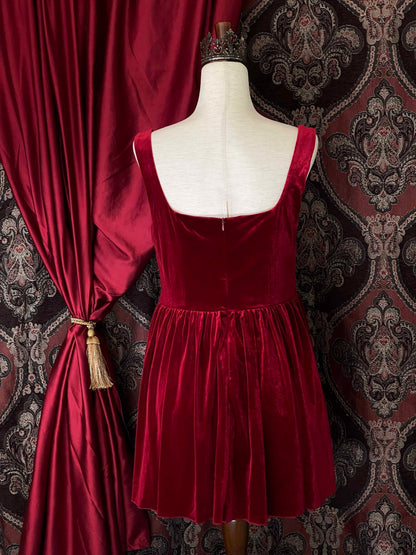 A renaissance and tudor era inspired red velvet mini dress with structured corset style bodice, pictured on a mannequin in front of a historical background.