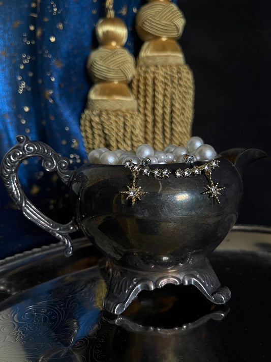 A pair of historically inspired fantasy astrology constellation star earrings in gold pictured in a whimsigoth celestial set.