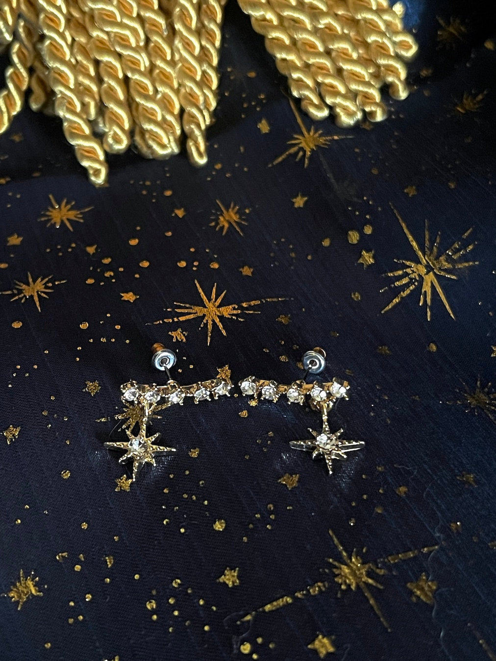 A pair of historically inspired fantasy astrology constellation star earrings in gold pictured in a whimsigoth celestial set.