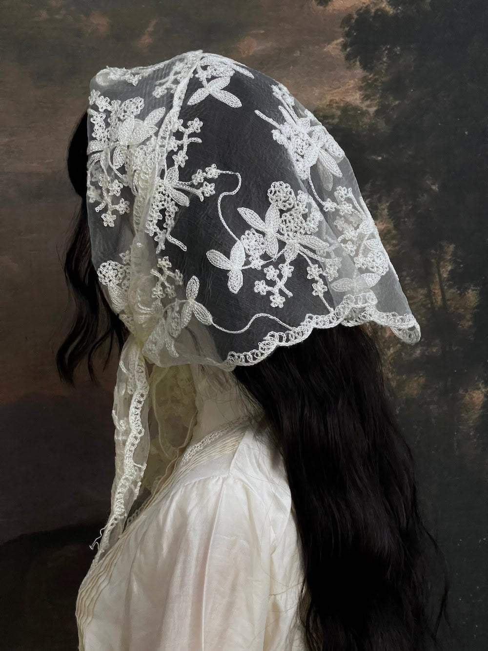 Mannequin wearing a vintage style ivory lace headscarf babushka triangle headdress made from floral embroidery lace against an art history background