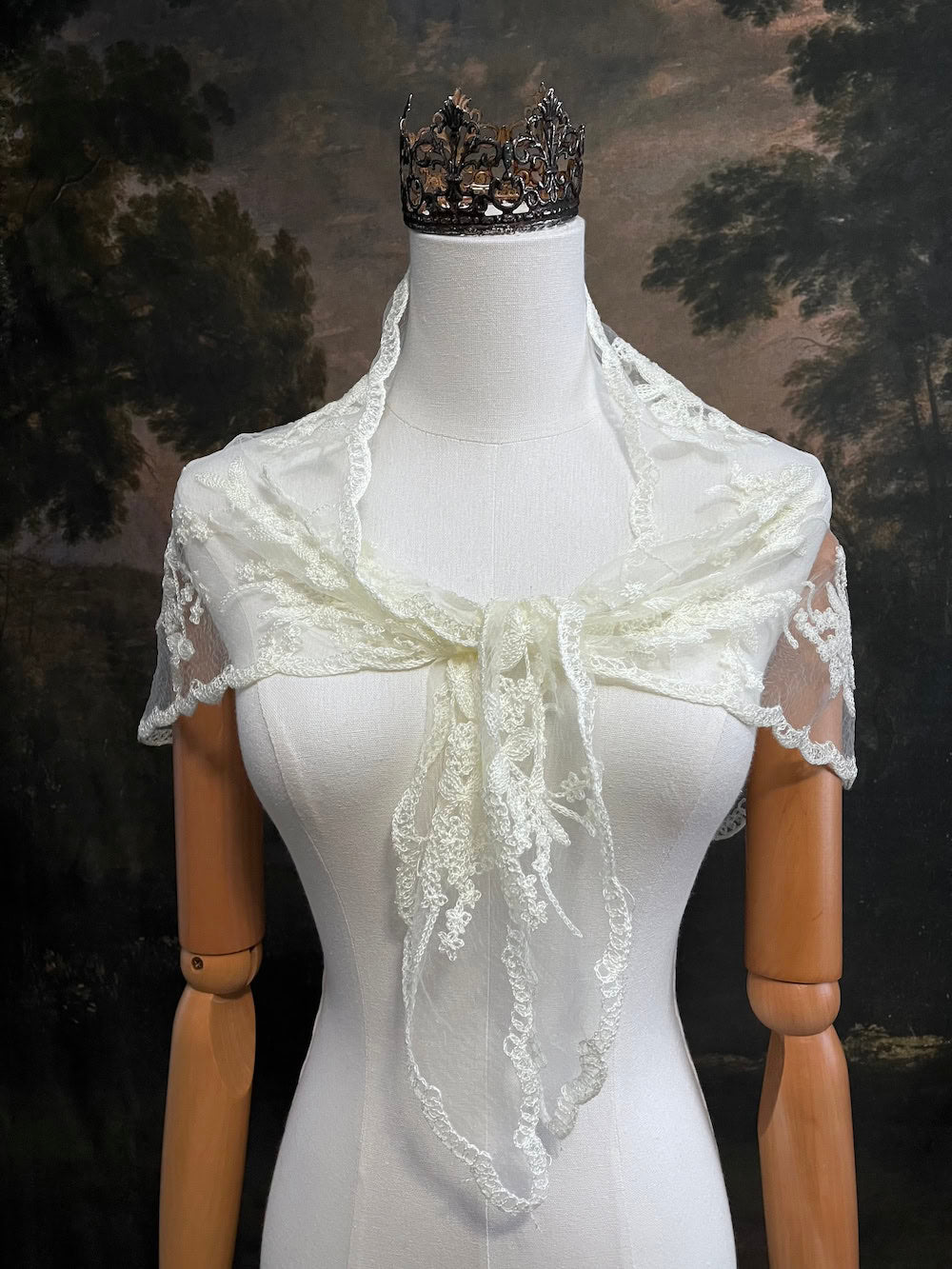 Mannequin wearing a vintage style ivory lace headscarf babushka triangle headdress made from floral embroidery lace as a shawl against an art history background