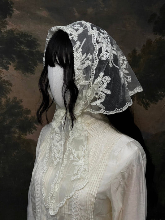 Mannequin wearing a vintage style ivory lace headscarf babushka triangle headdress made from floral embroidery lace against an art history background