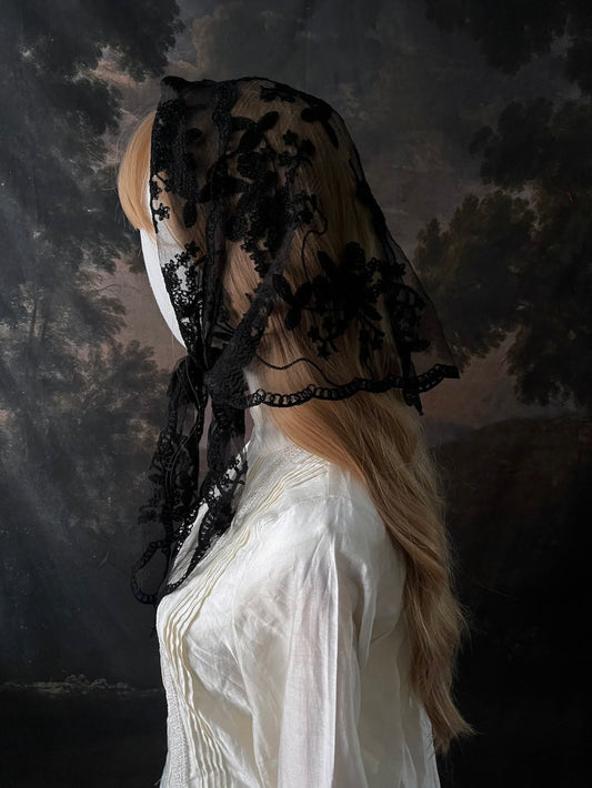 Mannequin wearing a vintage style gothic black lace headscarf babushka triangle headdress made from floral embroidery lace against an art history background