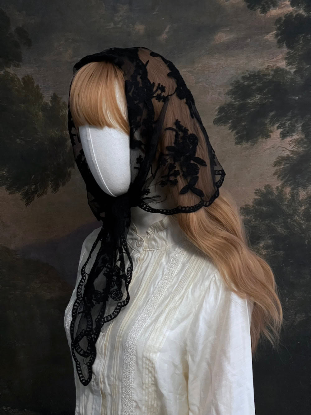 Mannequin wearing a vintage style gothic black lace headscarf babushka triangle headdress made from floral embroidery lace against an art history background