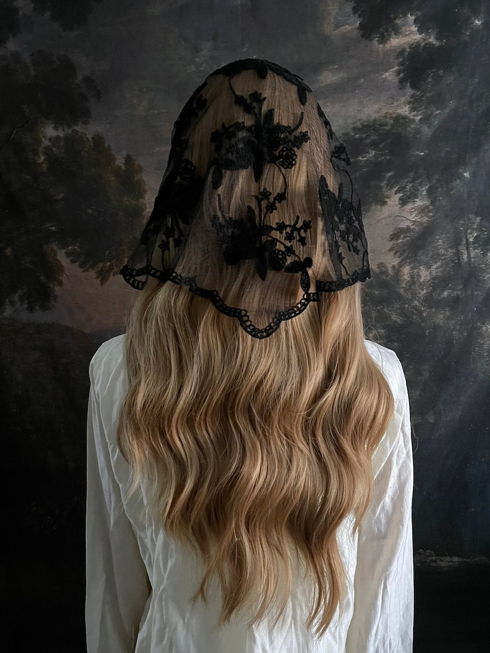 Mannequin wearing a vintage style gothic black lace headscarf babushka triangle headdress made from floral embroidery lace against an art history background
