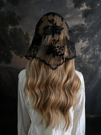 Mannequin wearing a vintage style gothic black lace headscarf babushka triangle headdress made from floral embroidery lace against an art history background