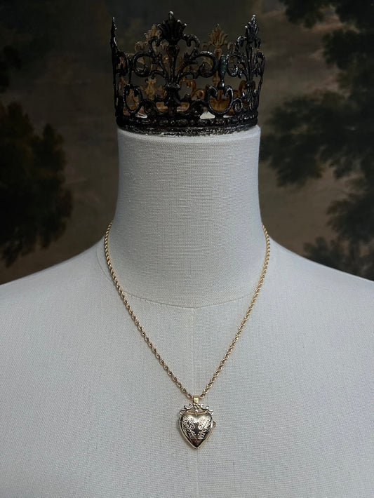Mannequin wearing a gold twisted chain with a heart shaped locket pendant carved with historically inspired floral filigree