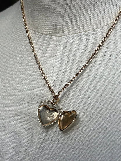 Mannequin wearing a gold twisted chain with a heart shaped locket pendant carved with historically inspired floral filigree