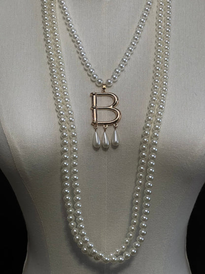 Mannequin wearing a Tudor inspired Anne Boleyn pearl necklace with a decorative 'B' pendant against a dark art history background