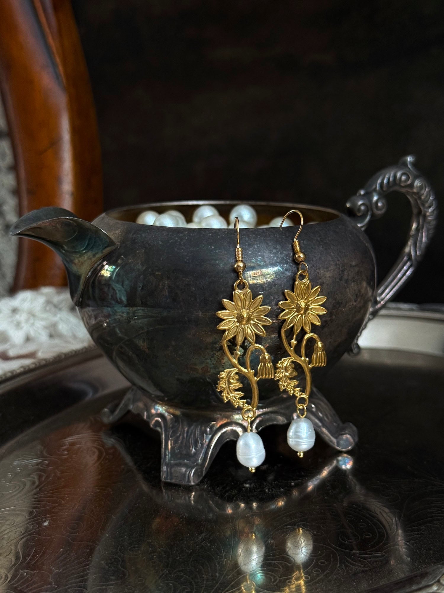 Historically inspired gold toned medieval wildflower daisy earrings with pearl dangle drops, displayed on an antique silver dish.