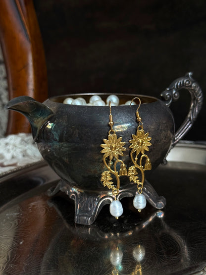 Historically inspired gold toned medieval wildflower daisy earrings with pearl dangle drops, displayed on an antique silver dish.