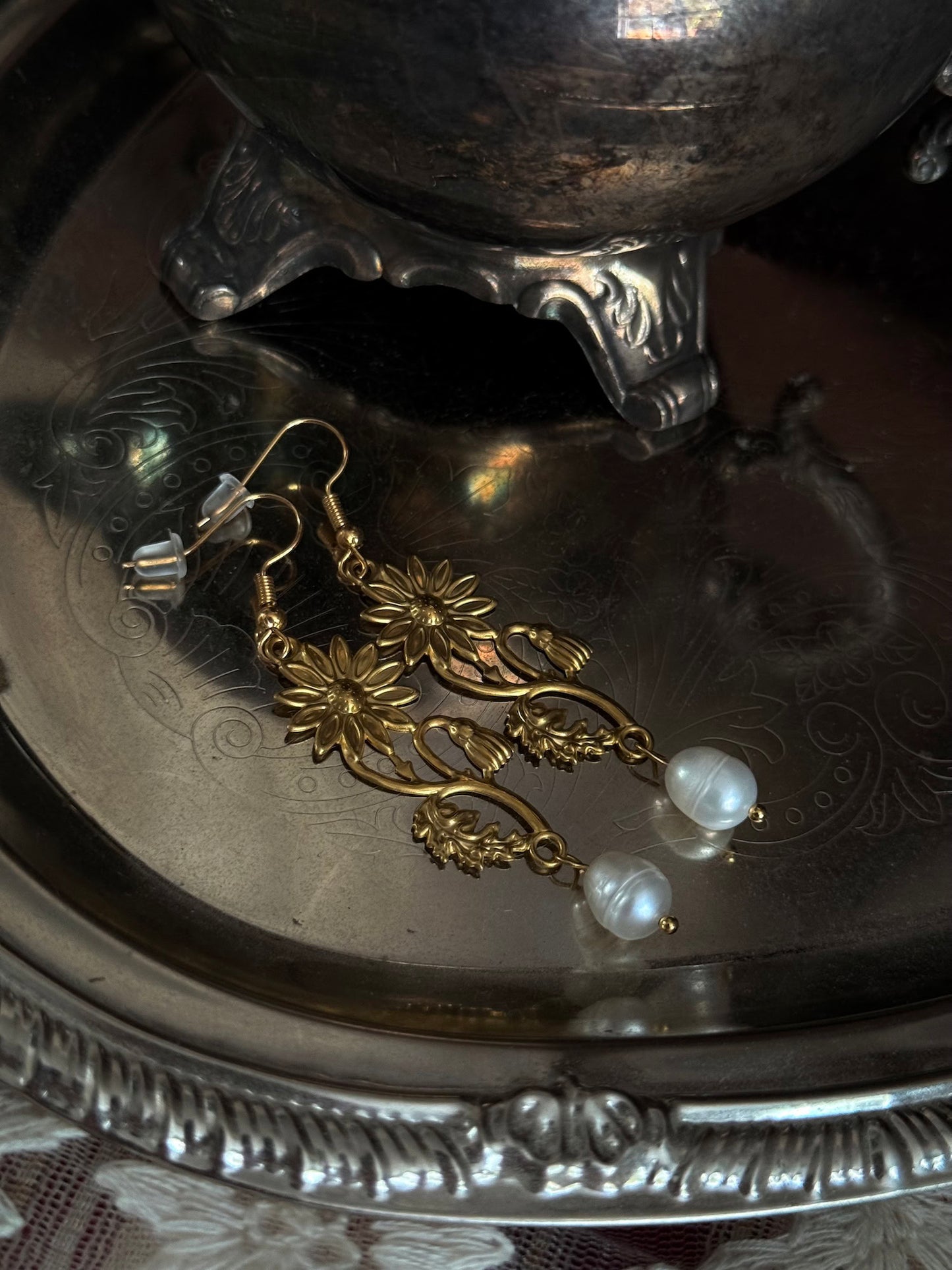 Historically inspired gold toned medieval wildflower daisy earrings with pearl dangle drops, displayed on an antique silver dish.