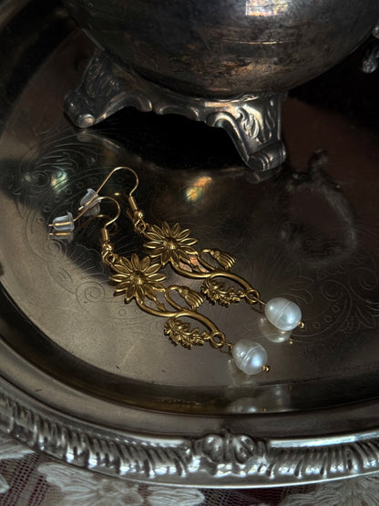 Historically inspired gold toned medieval wildflower daisy earrings with pearl dangle drops, displayed on an antique silver dish.