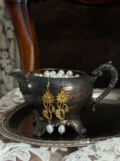 Historically inspired gold toned medieval wildflower daisy earrings with pearl dangle drops, displayed on an antique silver dish.
