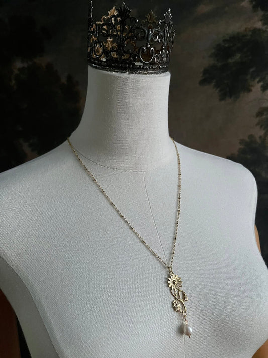 A historical jewelry inspired vintage style daisy flower pendant necklace with pearl dangle in gold toned stainless steel